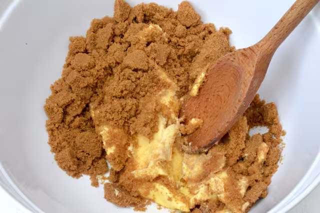 Softened butter and brown sugar in bowl with wooden spoon.