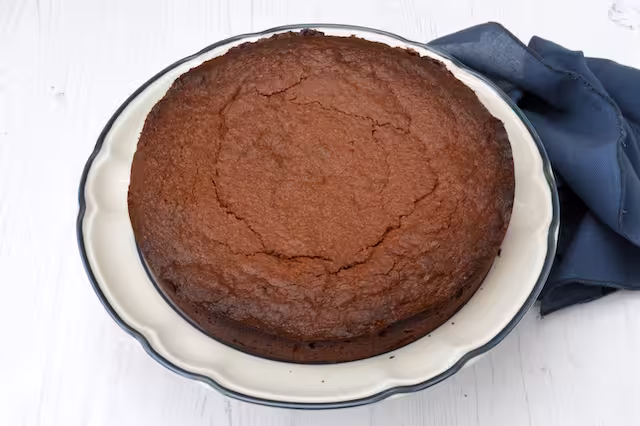 Almond chocolate cake on plate with navy napkin alongside.