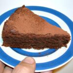 Slice of gluten-free chocolate almond cake on Cornishware plate.