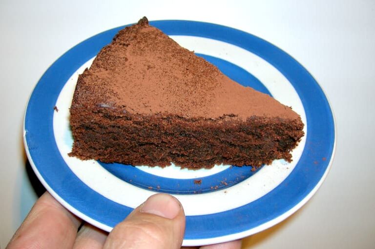 Slice of gluten-free chocolate almond cake on Cornishware plate.