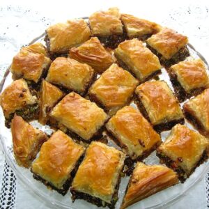 A plate full of chocolate baklawa on a white cloth.