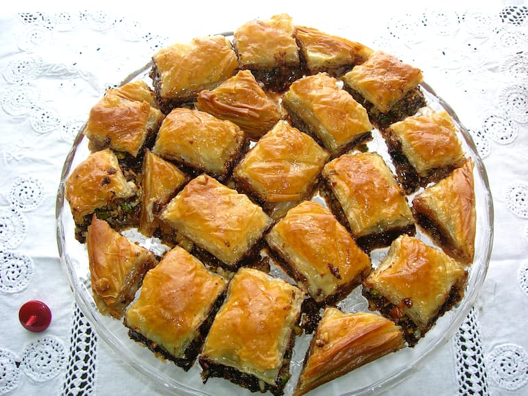 A plate full of chocolate baklawa on a white cloth.