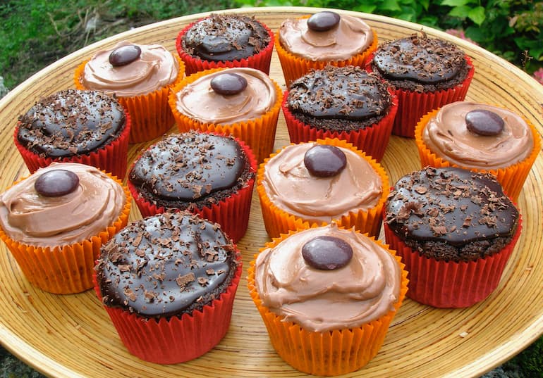 A tray of mixed milk and dark chocolate cupcakes in red and orange cases.