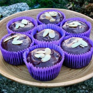 A tray of seven chocolate chestnut cupcakes in purple cases.