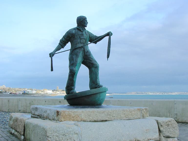 Statue of Newlyn fisherman on sea wall.