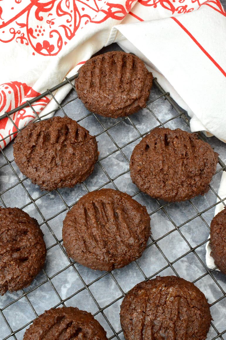 Cacao nib chocolate cookies in a cooling rack with cloth in background.
