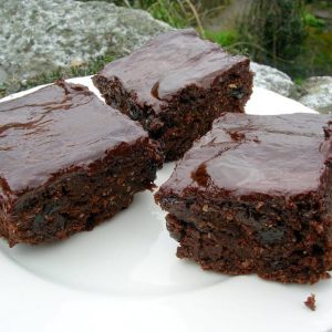 Three squares of chocolate raisin ale cake on a plate.