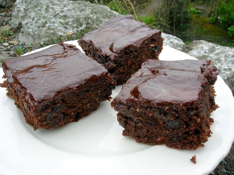Three squares of chocolate raisin ale cake on a plate.
