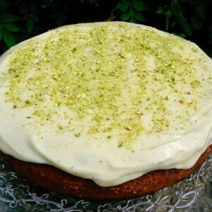 A round pistachio and orange blossom cake, decorated with mascarpone icing and roughly ground pistachio nuts.