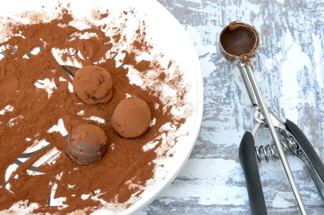 3 balls of ganache in a bowl, rolled in cocoa powder.