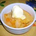 A bowl of apple and ground cherry Eve's Pudding with clotted cream.