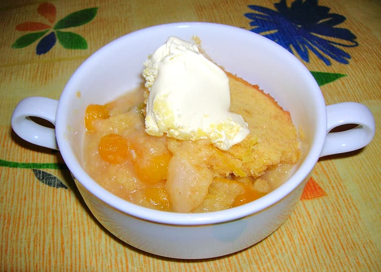 A bowl of apple and ground cherry Eve's Pudding with clotted cream.