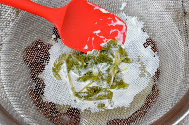 Lemon balm remaining in sieve after cream poured through.