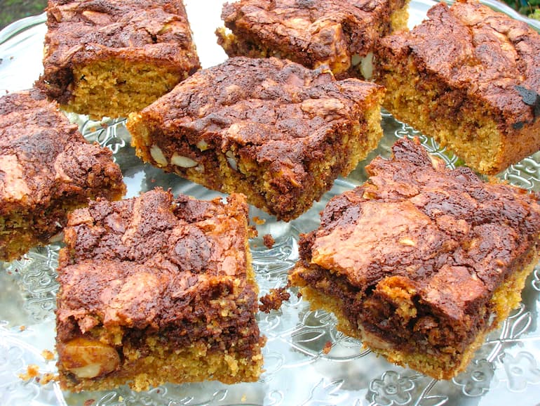 Several butterscotch swirl brownies on a glass cake stand.