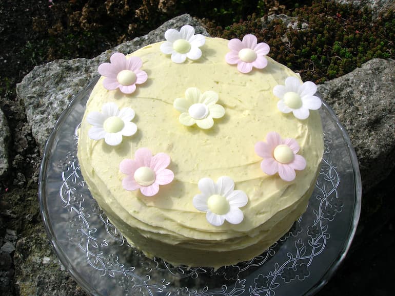Genoise sponge covered in lime and white chocolate icing with wafer daisies on the top.