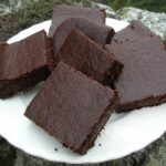 Triple chocolate ale brownies piled on plate.