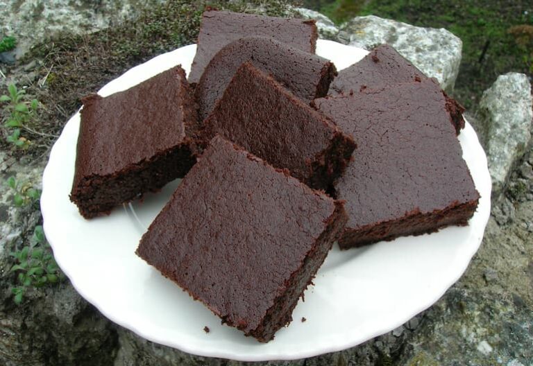 Triple chocolate ale brownies piled on plate.