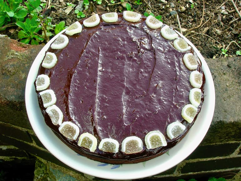 A chocolate marmalade plate on a wall, covered in ganache and decorated with orange jelly slices.