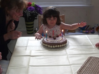 Three year old Jessica blowing out the candles on her birthday cake.