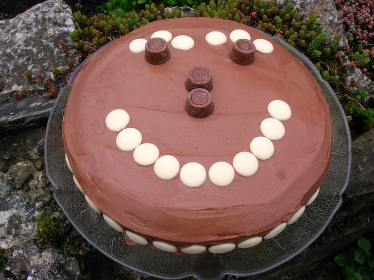 A chocolate rolo cake with a smiley face made out of white chocolate buttons and rolos.