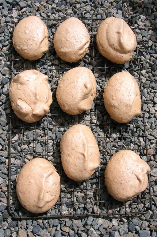 Rose meringues cooling on a rack outside.