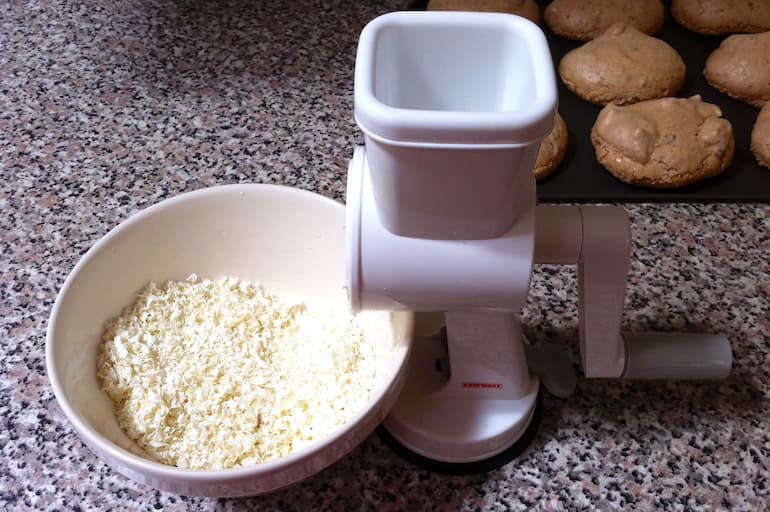 A bowl of grated white chocolate with grater.