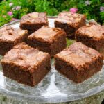 Chocolate courgette cake squares on glass stand.