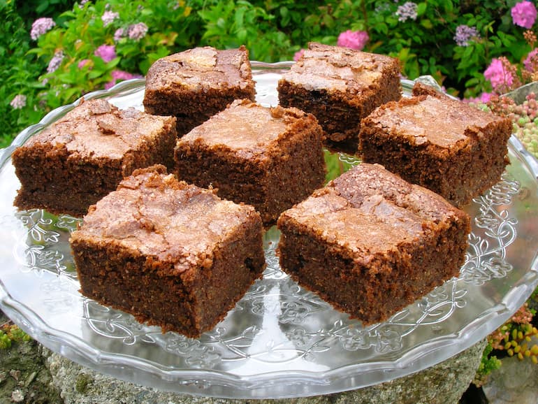 Chocolate courgette cake squares on glass stand.