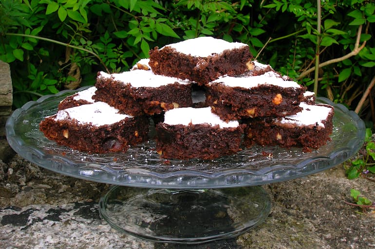 A stack of tropical brownies on a glass cake stand.