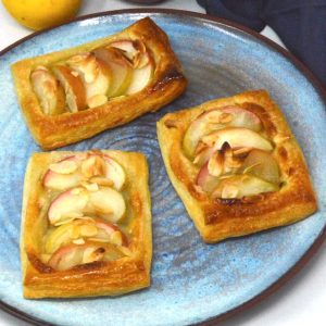 Three homemade apple and almond pastries on a blue plate.