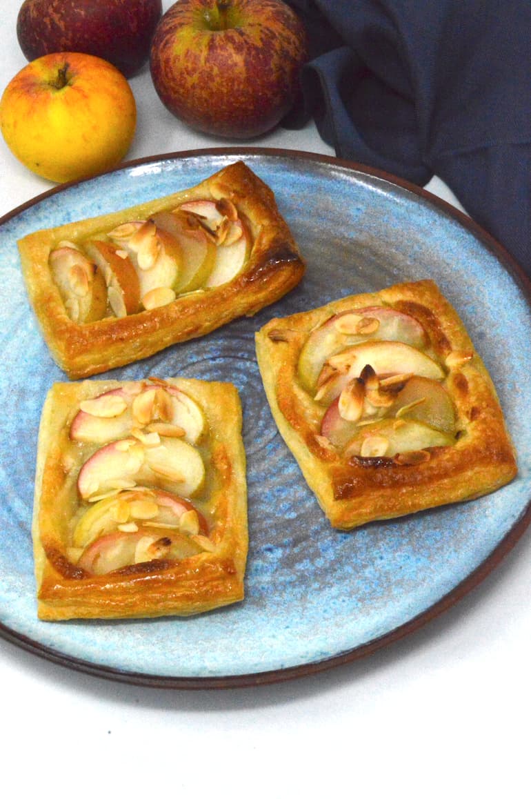 Three homemade apple and almond pastries on a blue plate.