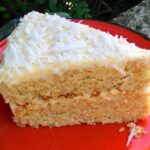Slice of Coconut milk layer cake on red plate.