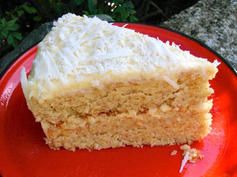 Slice of Coconut milk layer cake on red plate.