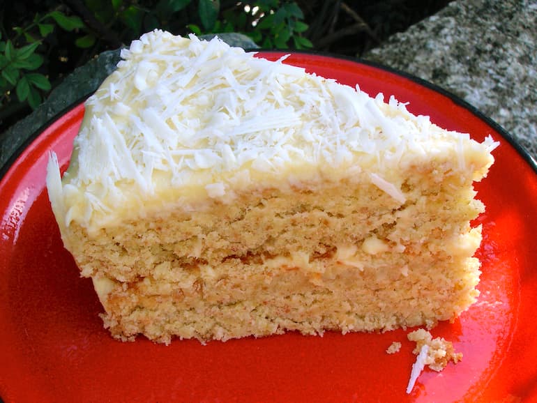 Slice of Coconut milk layer cake on red plate.