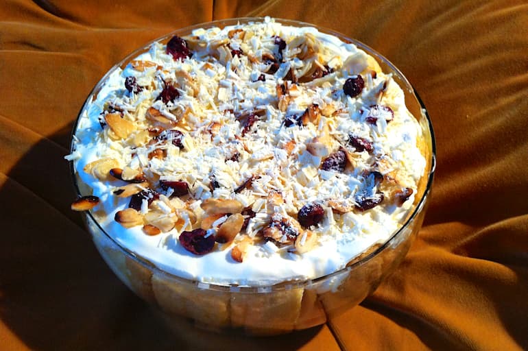A bowl of cranberry Christmas trifle on an amber coloured cushion.