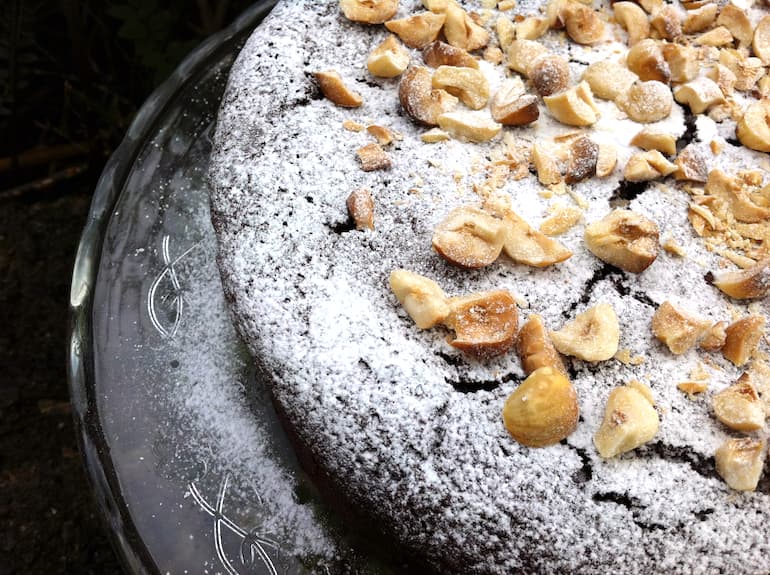 Partial view of a sherry chocolate hazelnut cake scattered with roasted hazelnuts.