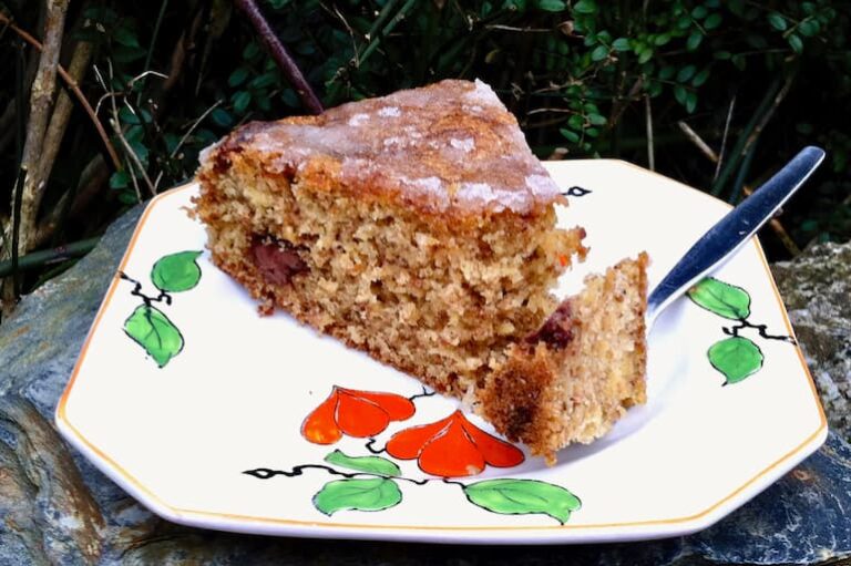 Slice of parsnip and walnut cake on tea plate with fork.