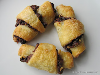 Three chocolate and cherry rugelach on a plate.