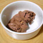 A bowl of slightly melted chocolate brownie ice cream.