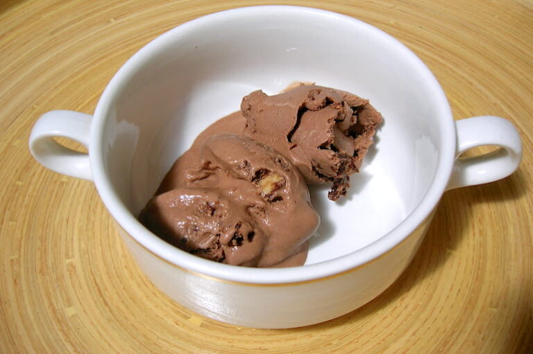 A bowl of slightly melted chocolate brownie ice cream.