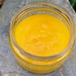 An open jar of homemade passionfruit curd.