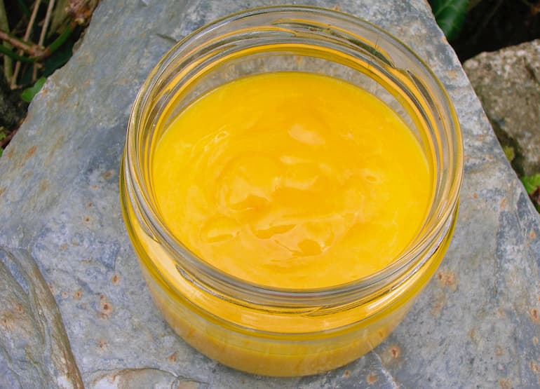 An open jar of homemade passionfruit curd.