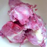 Scoops of homemade blackcurrant and white chocolate ripple ice cream in bowl.