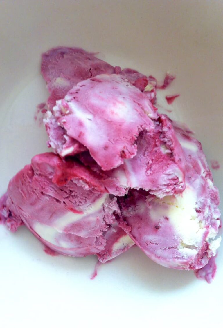 Scoops of homemade blackcurrant and white chocolate ripple ice cream in bowl.