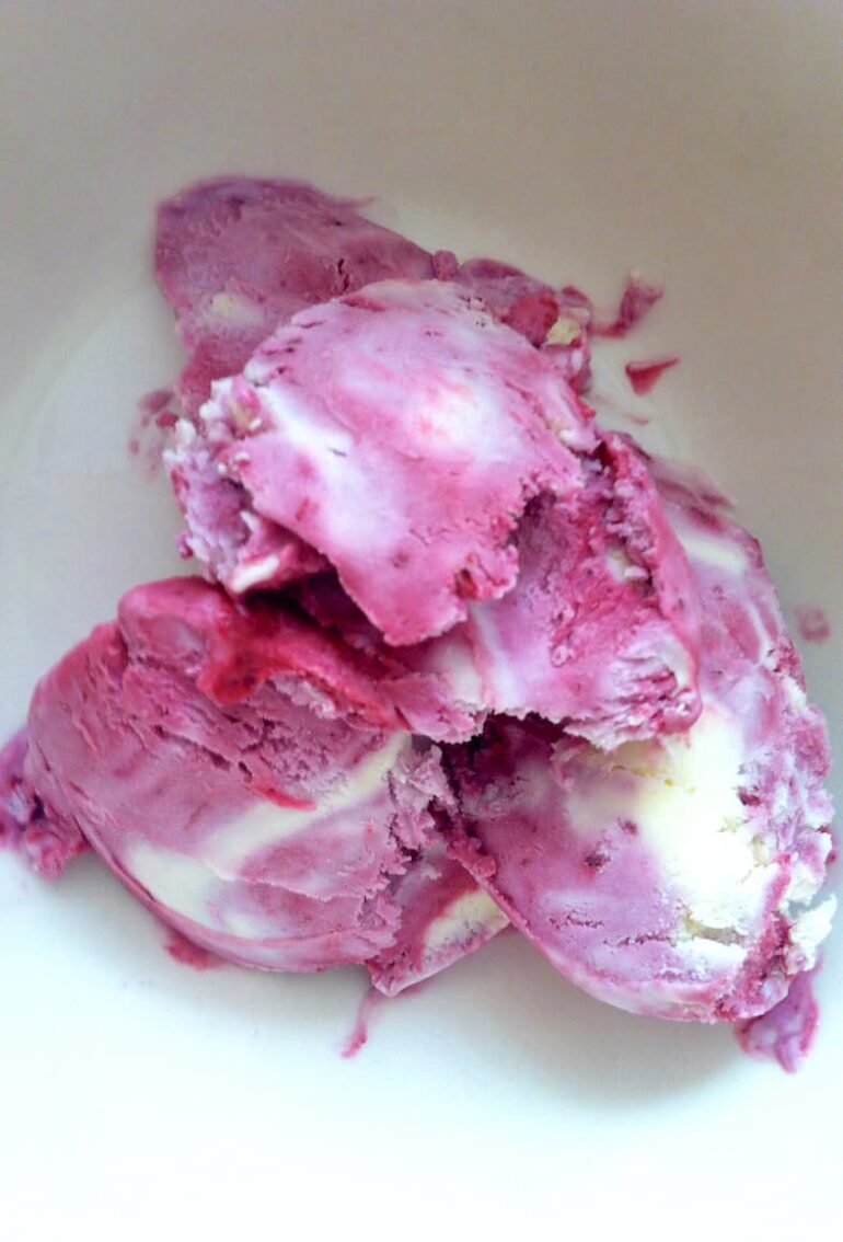 Scoops of homemade blackcurrant and white chocolate ripple ice cream in bowl.