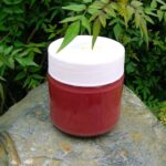 A jar of raspberry and rose curd sitting on a wall.