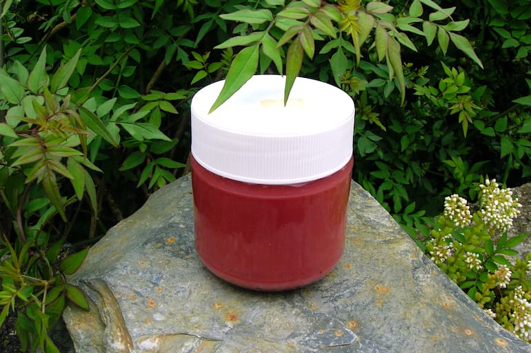 A jar of raspberry and rose curd sitting on a wall.