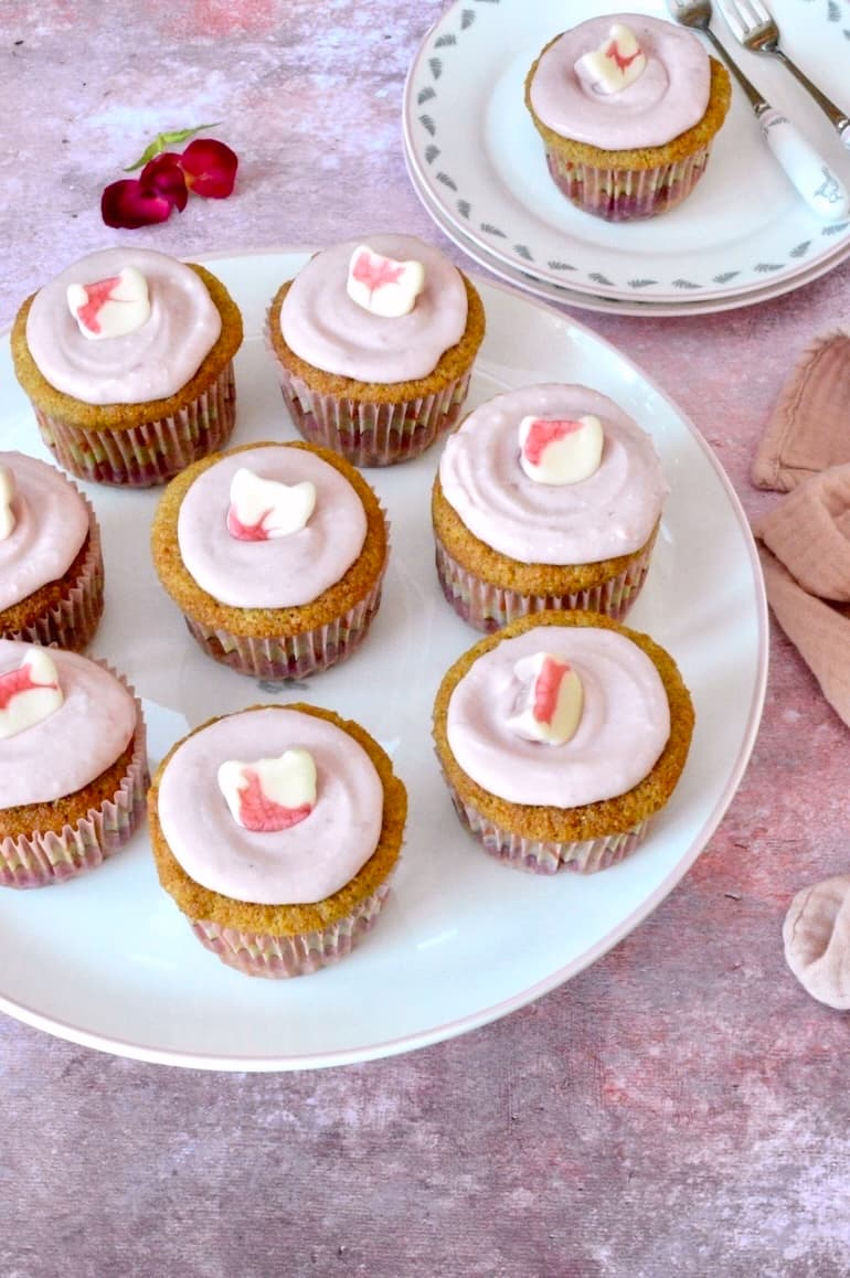 Stand of homemade raspberry curd cupcakes with one on plate with forks.