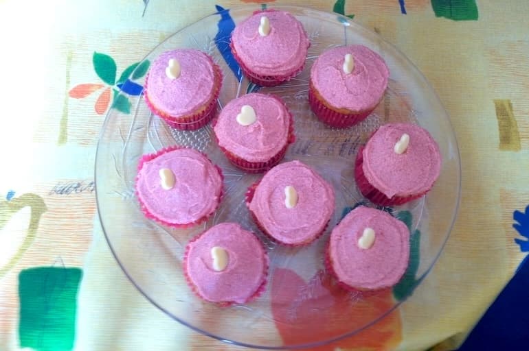 Glass plate holding homemade raspberry curd cupcakes.