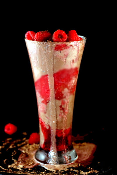 A chocolate champagne float in a tall glass with raspberries.